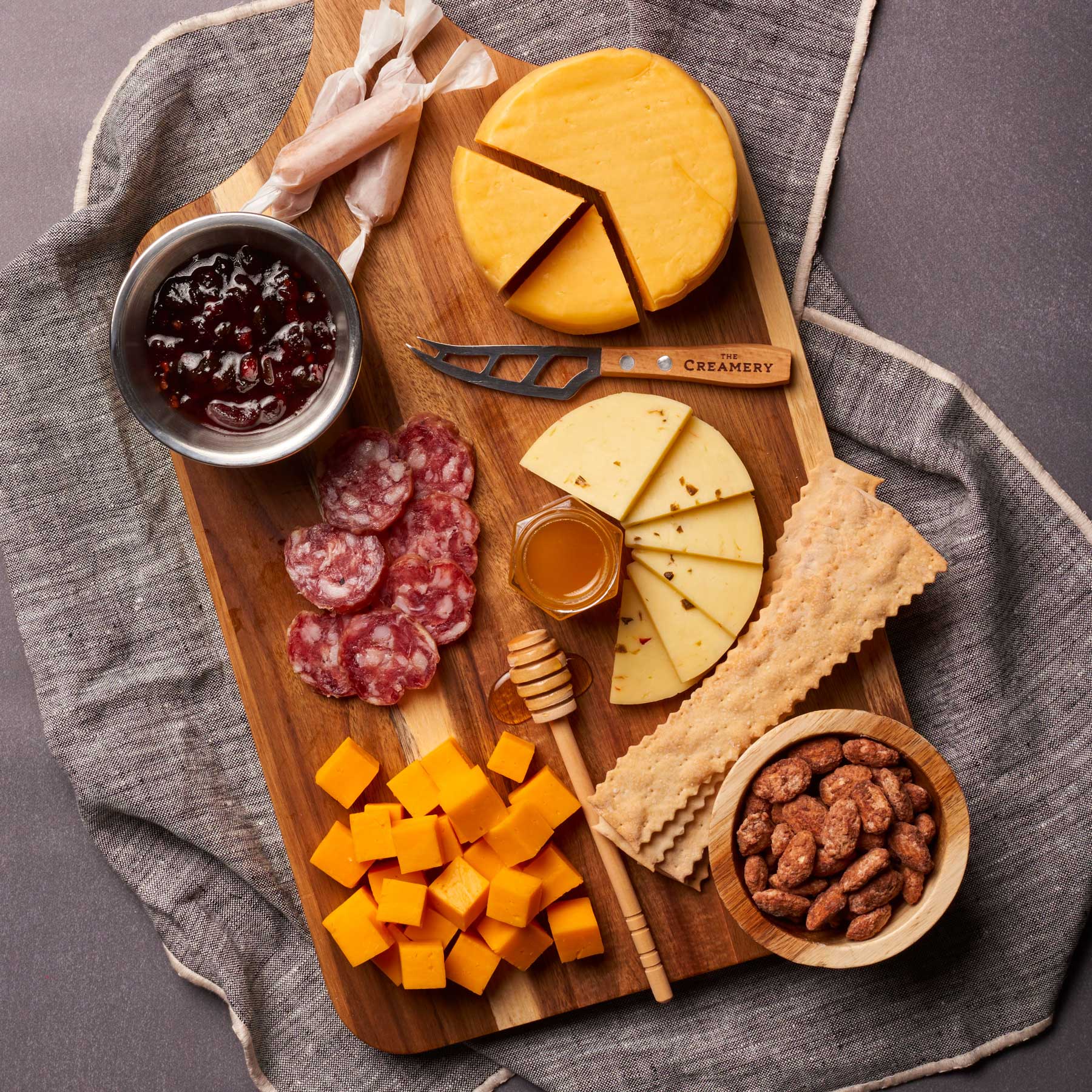 image of cheese board featuring jam, cheese, honey, nuts and cured meat