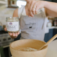 Women baking in the kitchen and sprinkling Blue Cattle Mexican Vanilla Bean Sugar from The Creamery