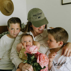 Mom holding bouquet of roses with her three children and wearing The Creamery Relaxed Twill Hat in color Moss Green